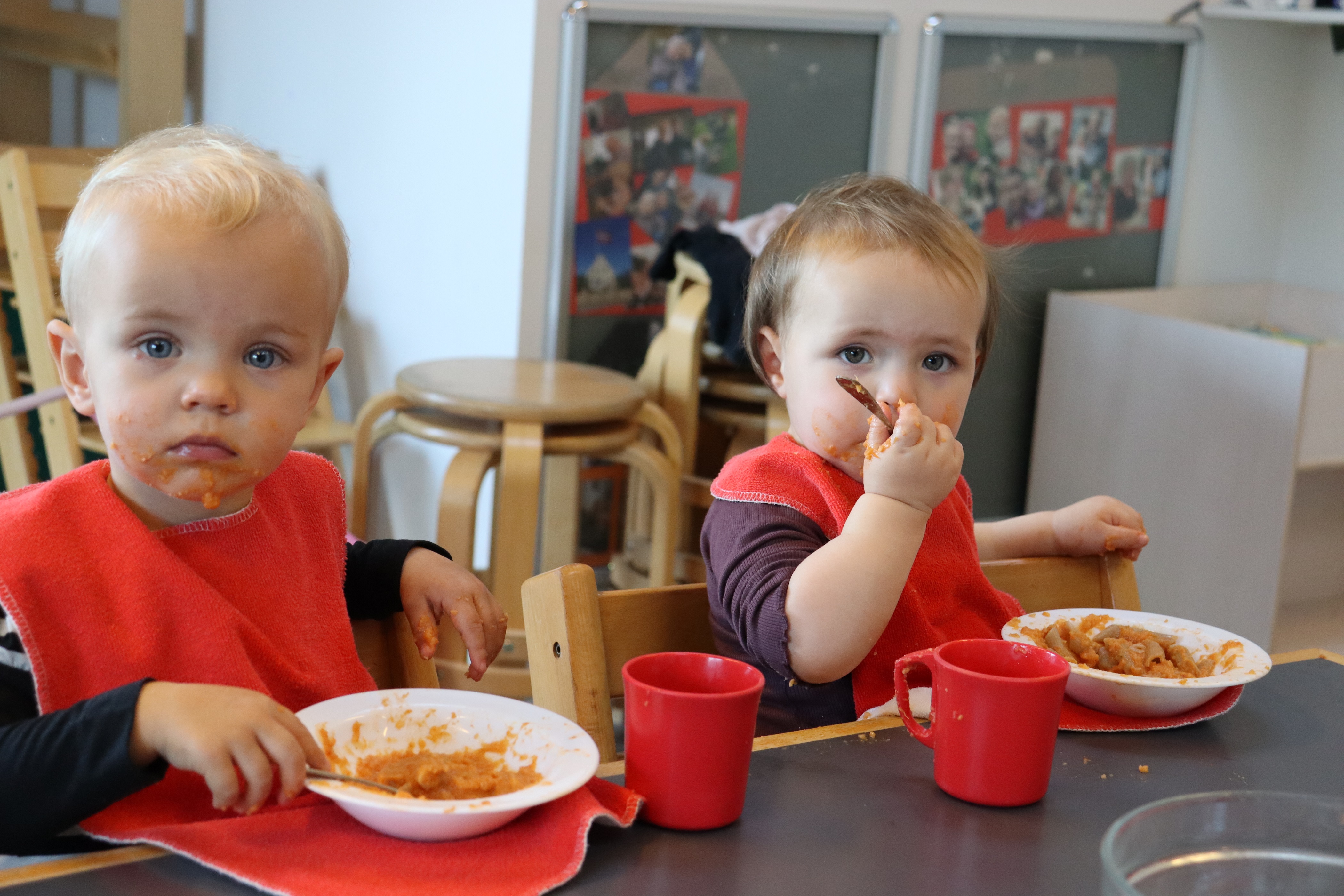 To vuggestuebørn spiser frokost med ske og skål